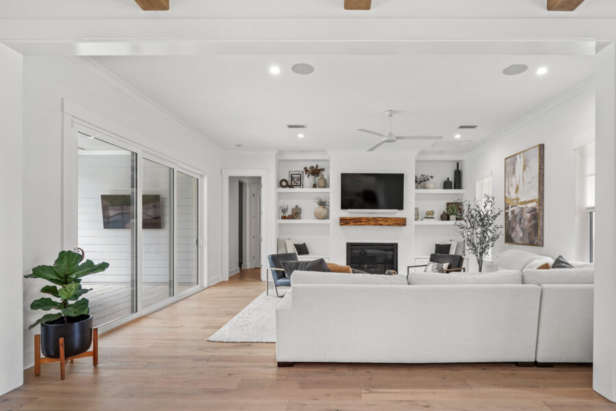 Modern living room with white walls, large sliding glass doors, cozy white sectional sofa, contemporary fireplace, and minimalist decor creating an inviting and stylish space.