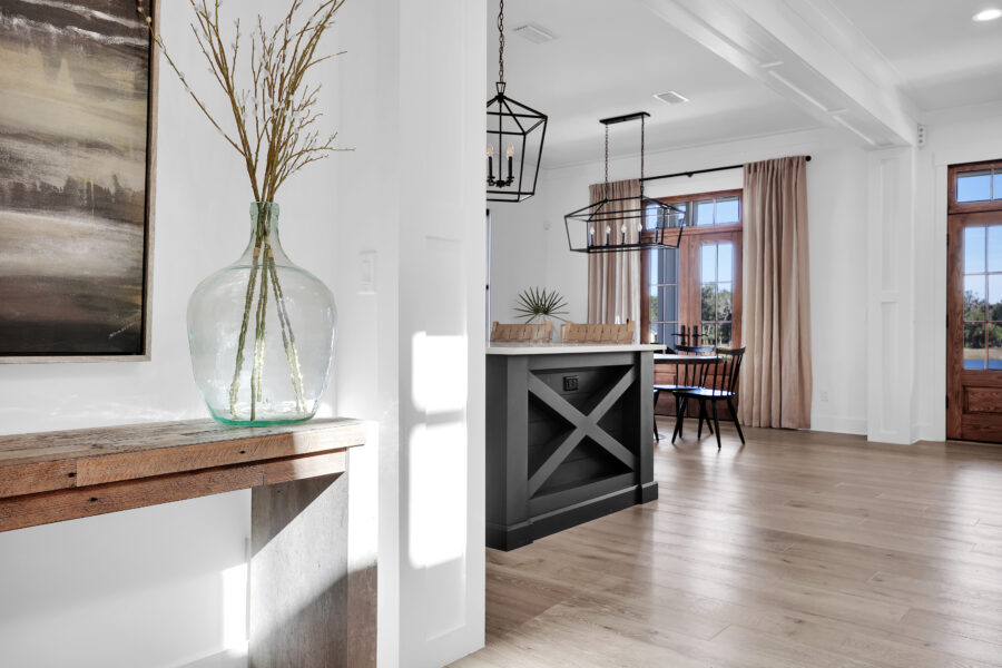 Bright, open living and dining area with large windows, wooden floors, modern lighting fixtures, and a neutral color palette, showcasing a stylish and inviting home interior.