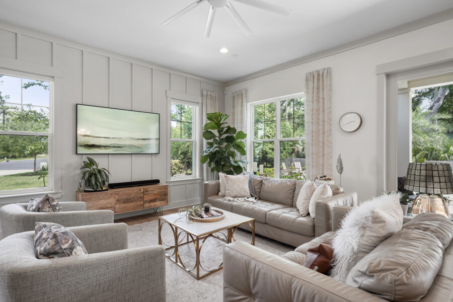 Modern living room with large windows, white walls, cozy beige sofas, and stylish decor, perfect for relaxation and entertaining.