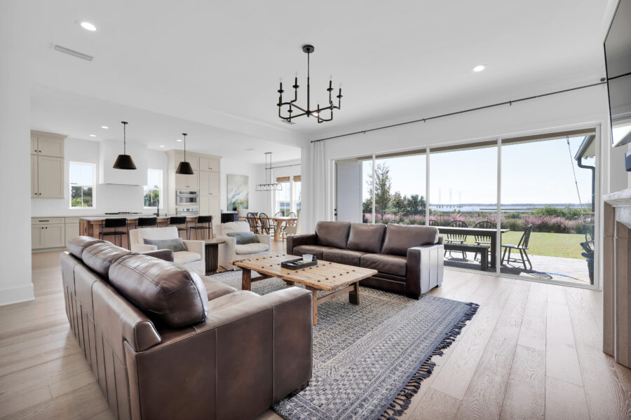 Spacious living room with leather sofas, a wooden coffee table, large windows, and a view of the outdoor patio, highlighting modern home design and open-concept layout.