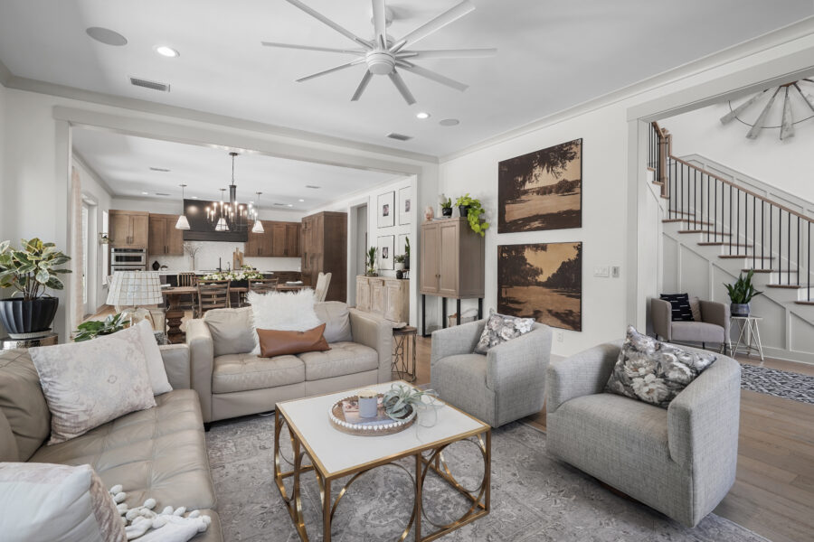 Modern open-concept living room with light-colored sofas, decorative pillows, and a view into the kitchen and dining area. Bright, airy space with stylish decor and ample natural light, perfect for family gatherings.