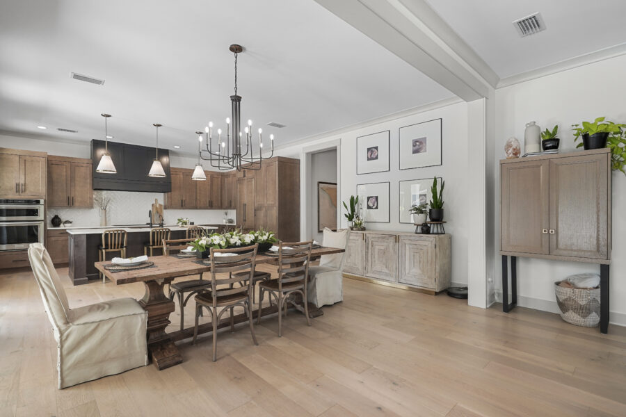 Bright open-concept kitchen and dining area with wooden cabinetry, modern lighting fixtures, and elegant decor, perfect for family gatherings and entertaining guests.