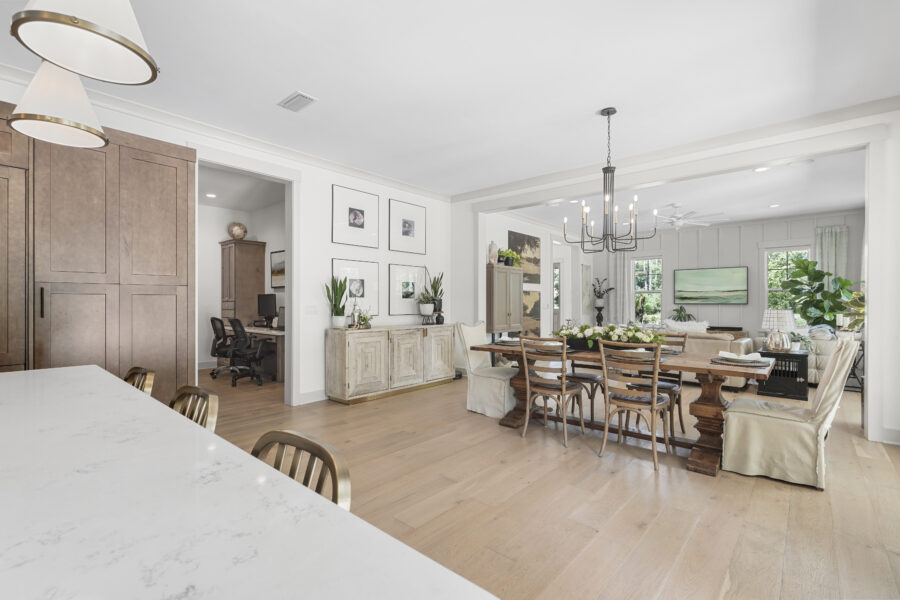 Bright open-concept dining and living area with large windows, neutral tones, wooden furniture, and modern decor, showcasing a stylish and comfortable home interior.