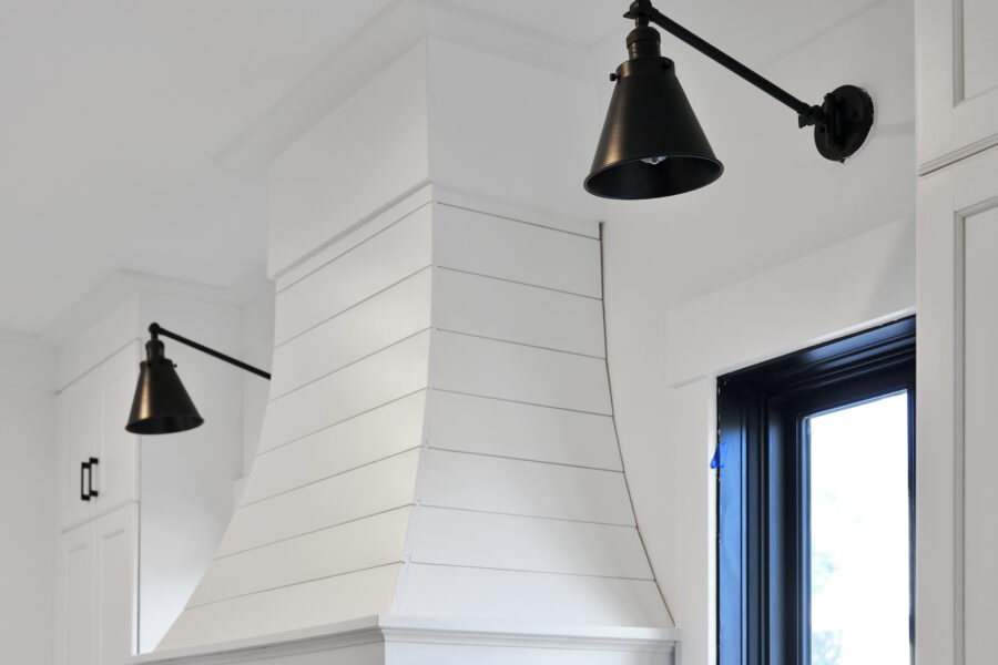 Modern white kitchen interior with black pendant lighting and cabinetry, featuring a black-framed window for natural light, showcasing stylish and contemporary home design.