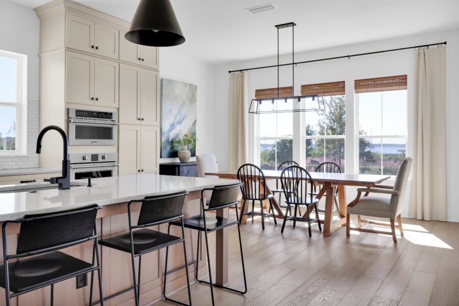 Modern kitchen with white cabinetry, large island with seating, and ample natural light from big windows, showcasing a bright and airy open-concept design.
