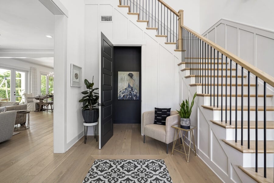 Contemporary home interior featuring a staircase with wooden steps and black railings, a cozy seating nook with plants, modern decor, and natural light illuminating the living space.