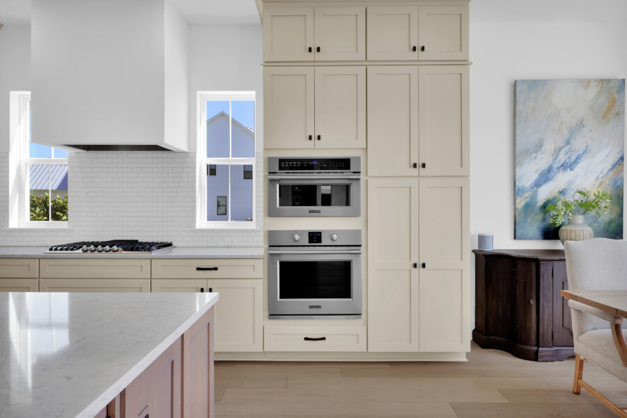 Modern kitchen with built-in double oven, white cabinetry, and large windows offering natural light and scenic views.