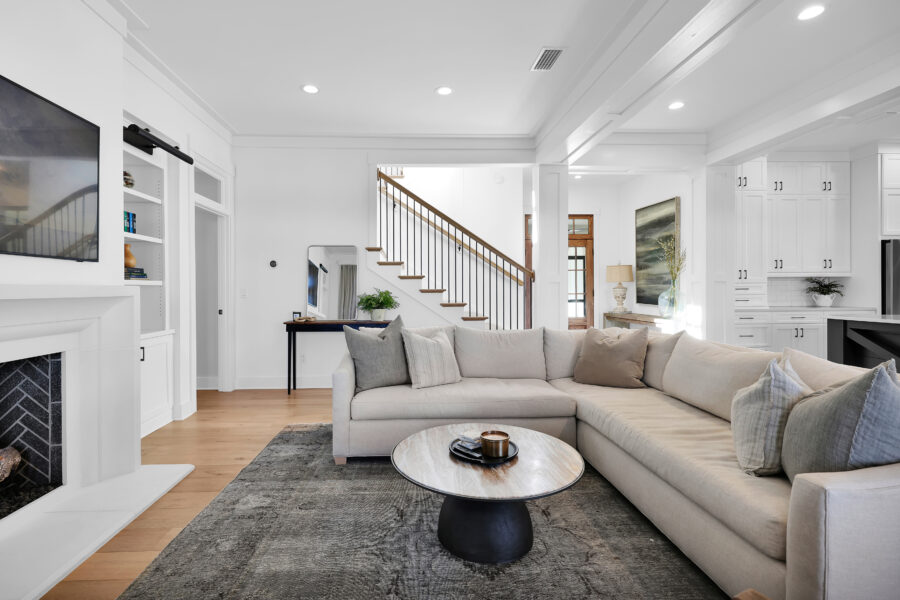 Modern living room with white walls, hardwood flooring, and stylish furniture, showcasing a spacious and bright interior featuring a sectional sofa, fireplace, and contemporary decor elements.