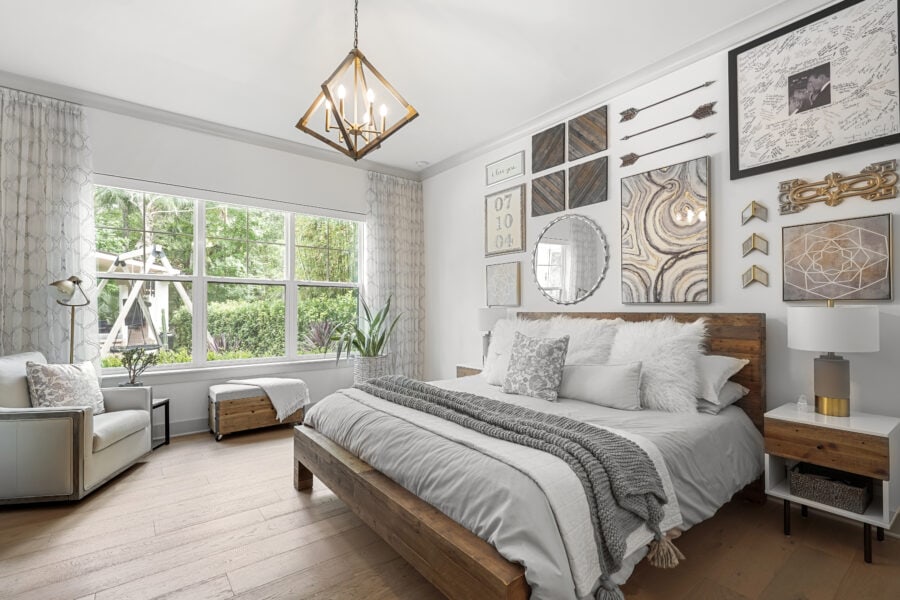 Luxurious master bedroom with a wooden bed frame, contemporary wall art, cozy pillows, and large windows overlooking a lush garden. Modern lighting and elegant decor create a relaxing atmosphere.