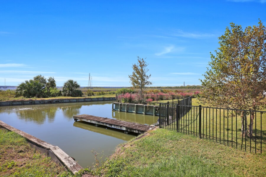 Floating dock on canal with lush greenery and clear blue sky in the background.