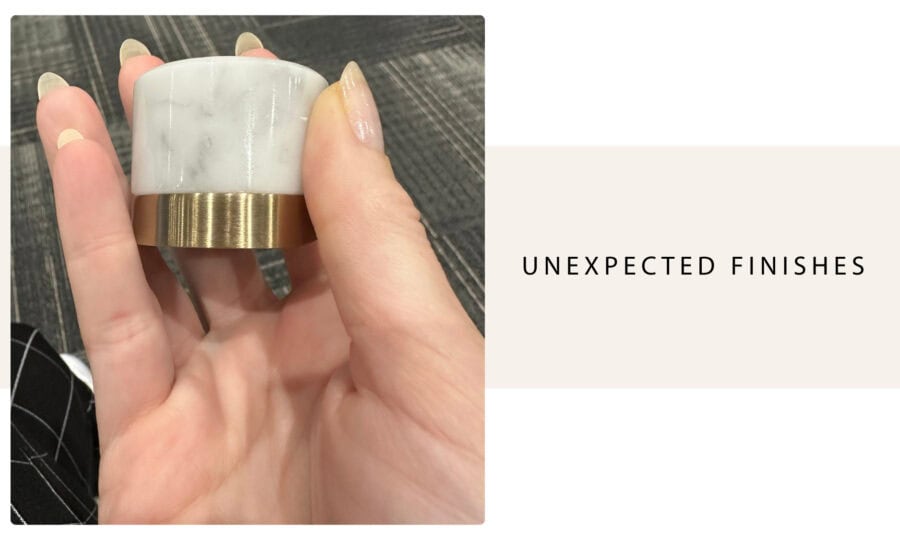 Polished marble and brass ring with unexpected finish detail, held by a person with manicured nails, showcasing a modern jewelry design.