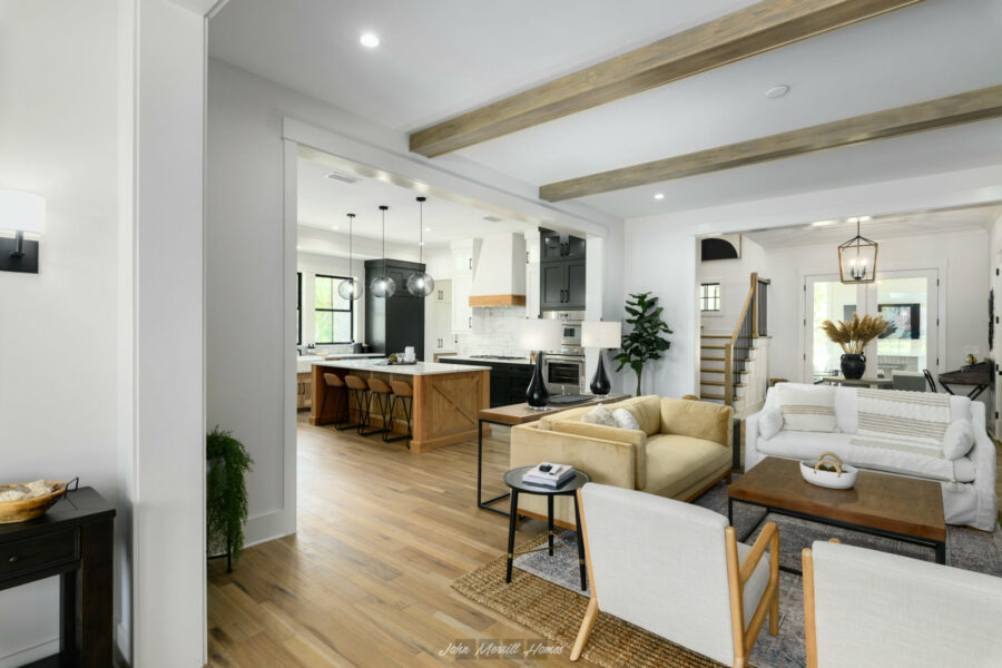 Bright open-concept living area with modern decor, featuring a cozy seating arrangement, stylish lighting, and natural light highlighting the white walls and wooden accents.