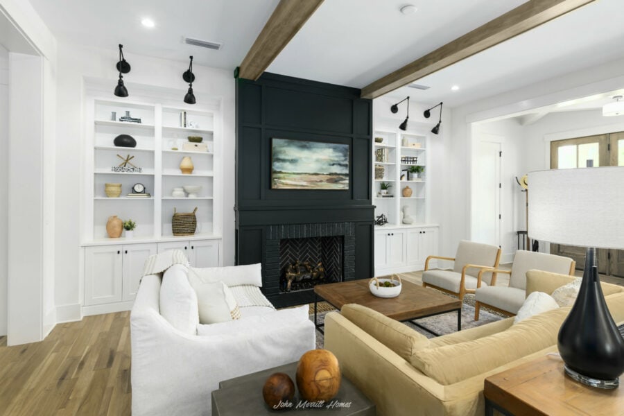 Modern living room with built-in white bookshelves, a black fireplace with a landscape painting, white and beige seating, wooden accents, and contemporary decor, bright and inviting interior design.