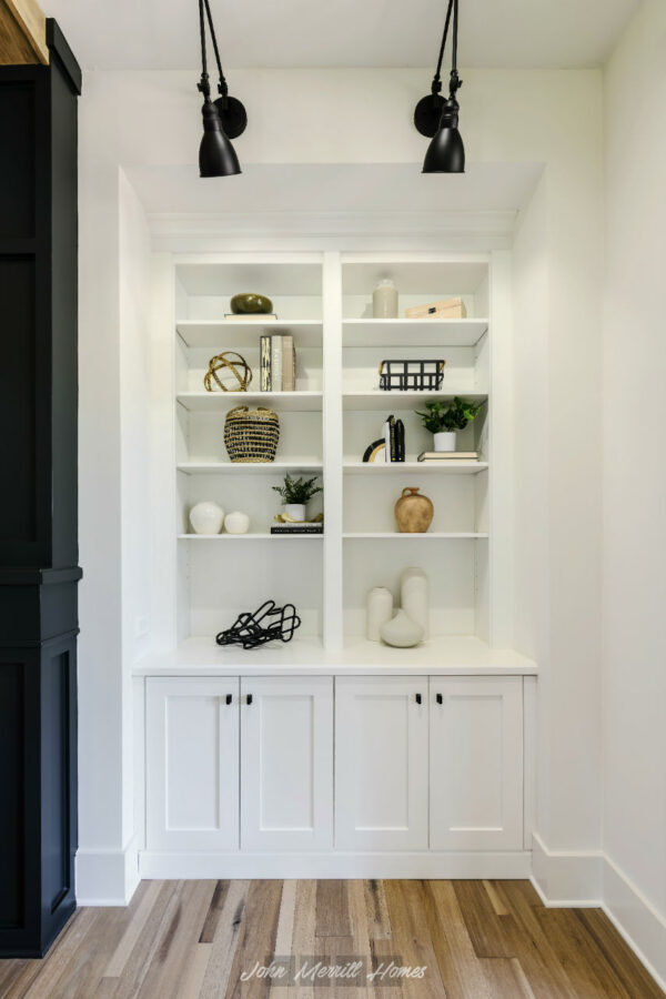 Beautiful white built-in bookshelf with decorative vases, books, and greenery in a modern home interior.