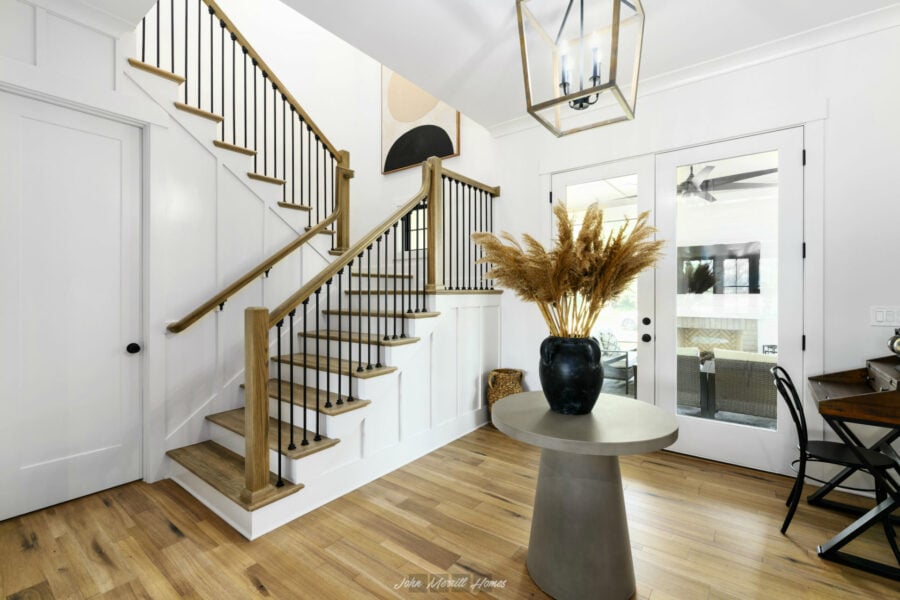 Modern staircase with wooden steps and black railing in a bright, stylish home interior.