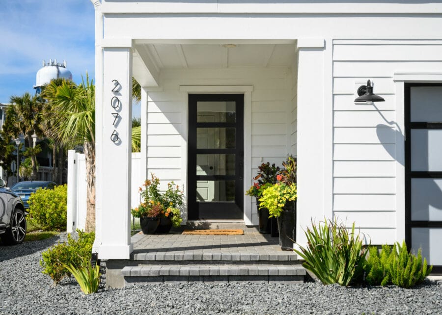 2076 house number sign on white siding exterior home with front door and potted plants, showcasing a modern and inviting entrance design.