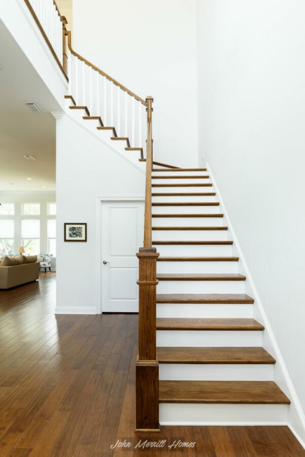 Wooden staircase with white risers and a wooden handrail in a modern home interior.