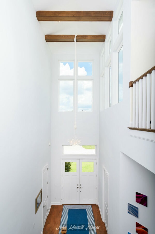 Bright, spacious entryway with high vaulted ceilings, large windows providing natural light, and a modern interior design showcasing clean white walls and wooden accents.