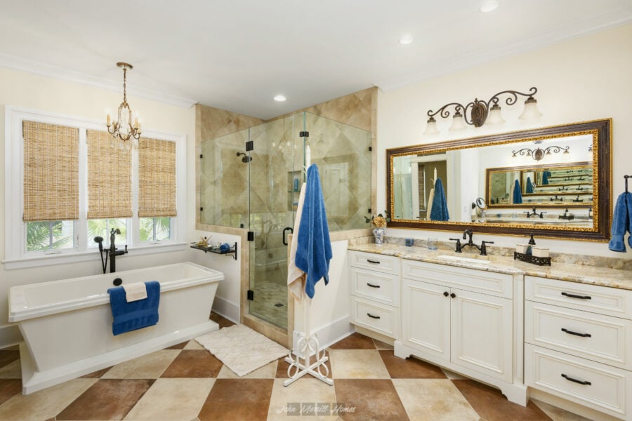 Luxury bathroom with a freestanding bathtub, double vanity with marble countertops, glass-enclosed shower, and elegant decor filled with natural light.
