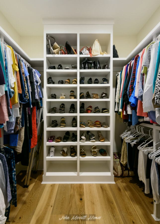 Spacious walk-in closet with organized shelves filled with shoes, handbags, and clothing, featuring hardwood flooring and ample storage space for a tidy, functional bedroom wardrobe.
