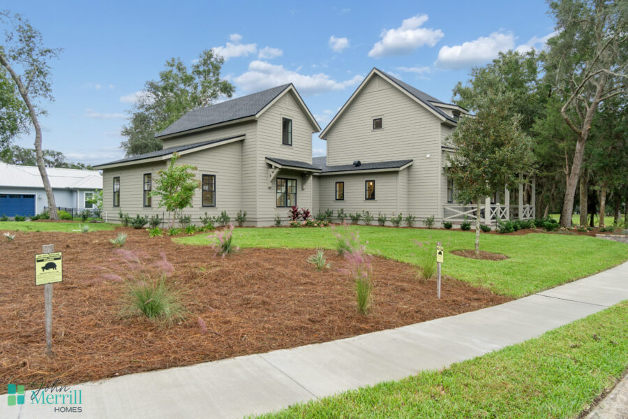 1. Modern newly constructed home with gray siding, black window frames, and a landscaped lawn in a suburban neighborhood.