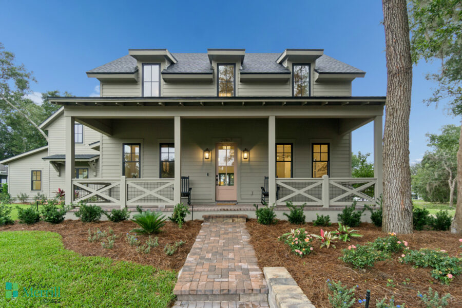 Luxurious modern home with a charming front porch, surrounded by lush greenery and colorful flowers, showcasing quality craftsmanship and elegant architectural details.