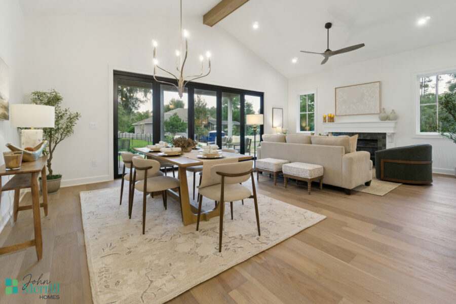 Bright, open-concept living and dining room with large glass sliding doors, modern decor, hardwood floors, a cozy fireplace, and stylish furniture creating a welcoming atmosphere.