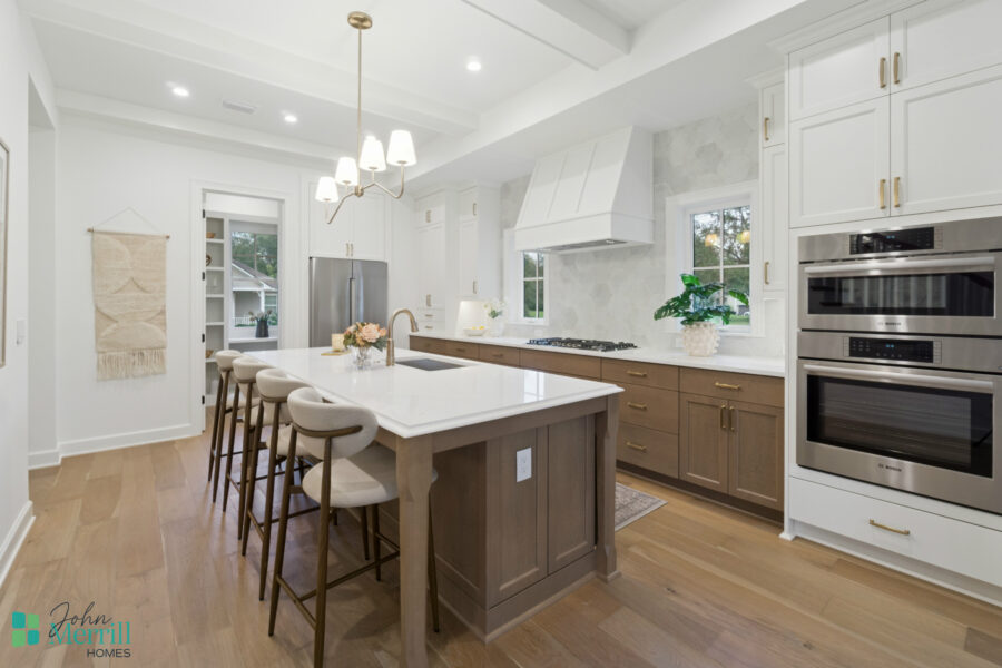 Bright modern white kitchen with wooden accents, large island with barstools, stainless steel appliances, and ample natural light from windows; designed for functionality and aesthetic appeal.