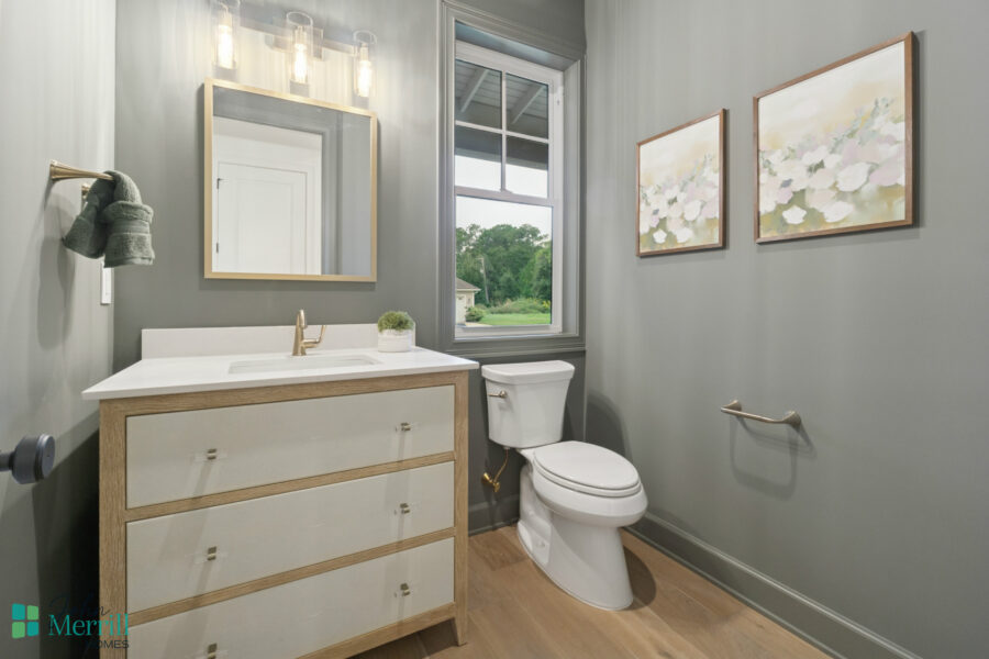 Bright and modern bathroom featuring a white vanity with natural wood accents, a wall-mounted mirror, elegant lighting fixture, and a scenic view through a large window.