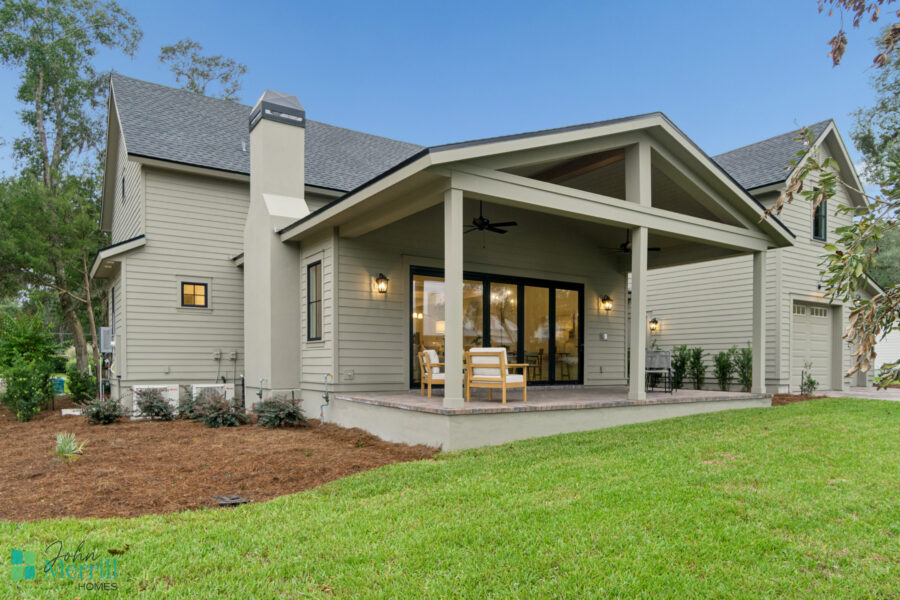 Bright, modern backyard patio with cozy seating area, surrounded by lush green lawn and landscaped plants, perfect for outdoor living in a single-family home.