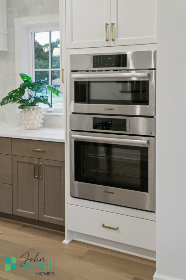1. Modern stainless steel Bosch wall ovens integrated into white cabinetry in a contemporary kitchen.