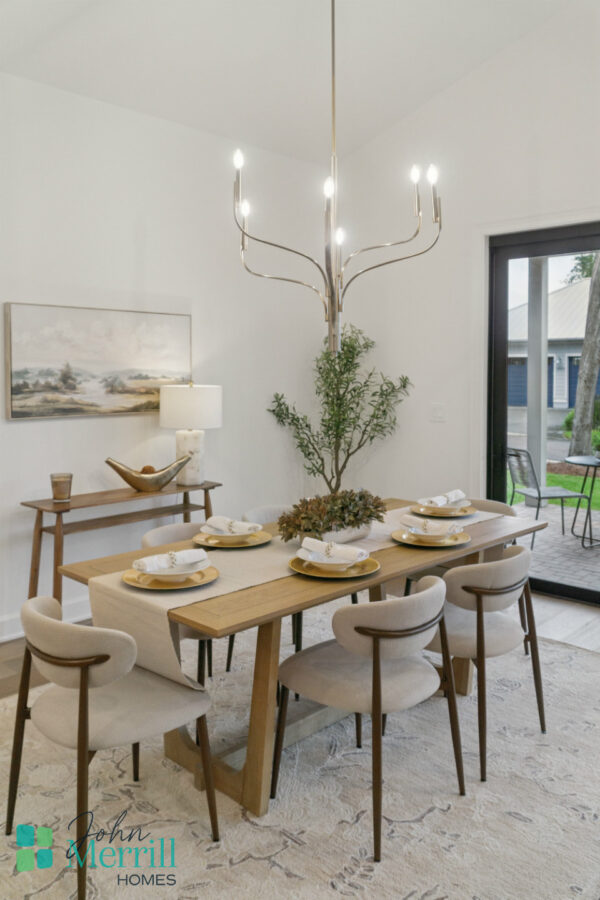 Bright modern dining room with a wooden table, eight upholstered chairs, contemporary chandelier, and large sliding glass door opening to outdoor patio.