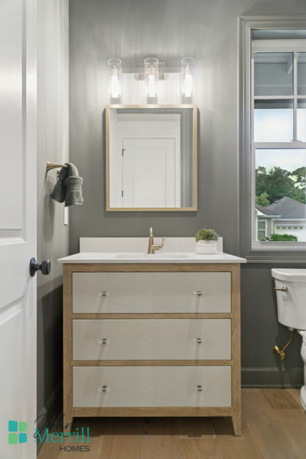 Bright bathroom vanity with a modern design, featuring a white marble countertop, a gold faucet, and a minimalistic mirror, illuminated by contemporary light fixtures, with a view of a sunrise from the window.