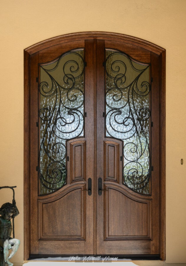 Elegant wooden front door with ornate wrought iron detailing, setting a welcoming tone for a beautiful home.