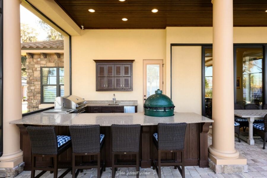 Outdoor kitchen with granite countertops, built-in grill, seating area, and stylish cabinetry, perfect for entertaining in a modern home.