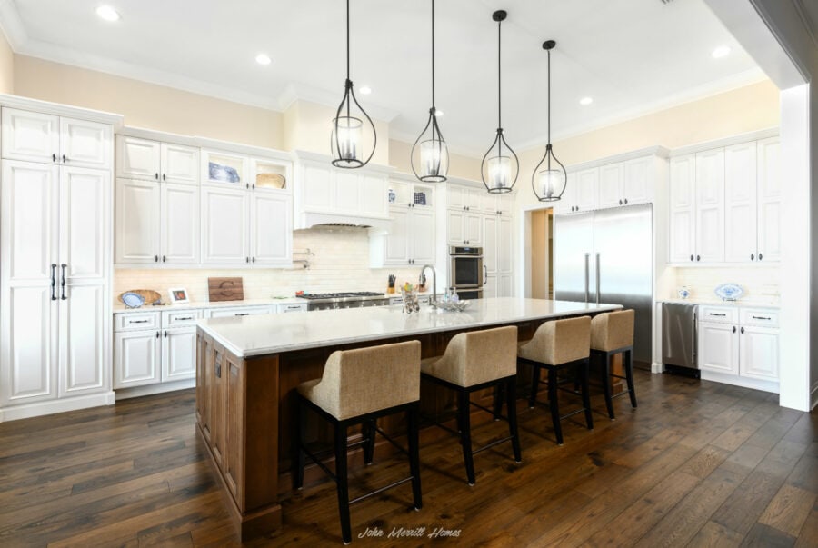 Bright white kitchen with a large island, elegant pendant lighting, and stainless steel appliances, featuring a cozy and modern design perfect for family cooking and entertaining.
