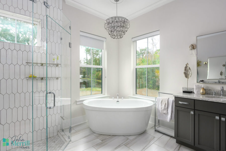 Elegant bathroom featuring a modern freestanding bathtub, large windows providing natural light, and a stylish glass-enclosed shower. Perfectly designed for comfort and relaxation.