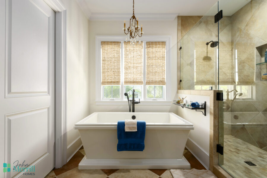 Elegant bathroom featuring a freestanding bathtub and a spacious walk-in shower with glass enclosure. Natural light fills the room through large windows with woven shades.