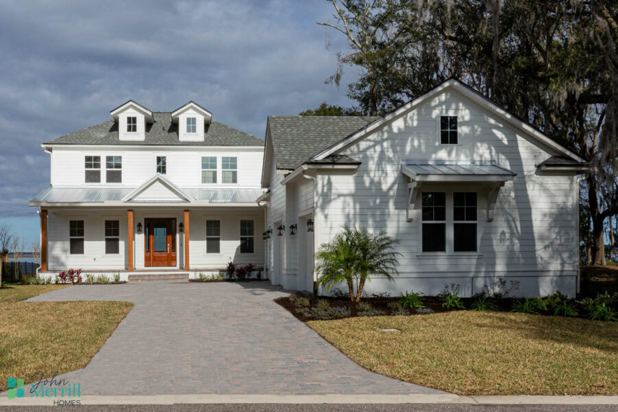 Beautiful white two-story home with a welcoming front porch, surrounded by a well-maintained lawn and landscaping, showcasing contemporary architectural design.