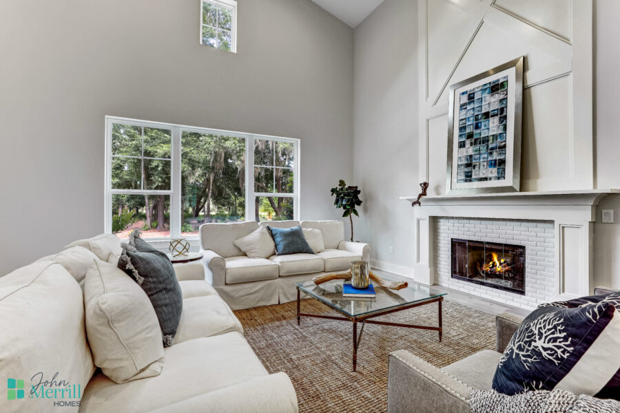 Elegant living room featuring a cozy fireplace, high vaulted ceilings, and large windows that let in natural light. The space is decorated with neutral tones and comfortable seating.