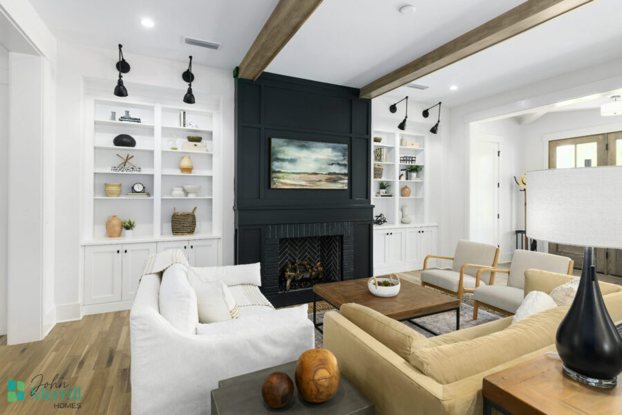 A welcoming living room featuring a central fireplace with a black surround, surrounded by white built-in shelves filled with decorative items, and furnished with beige and white sofas and armchairs.