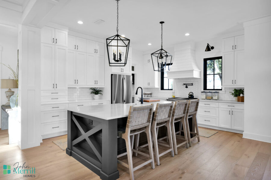 Modern white kitchen featuring a large island with seating, pendant lighting, and sleek cabinetry. Bright, airy space ideal for cooking and entertaining.