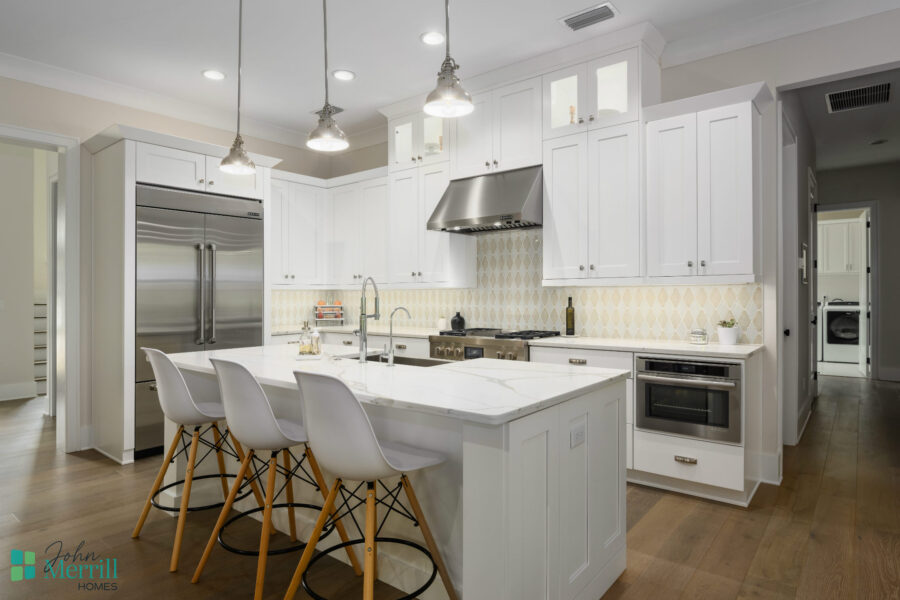 Bright, modern kitchen featuring white cabinets, stainless steel refrigerator, and island with seating, perfect for family cooking and entertaining.