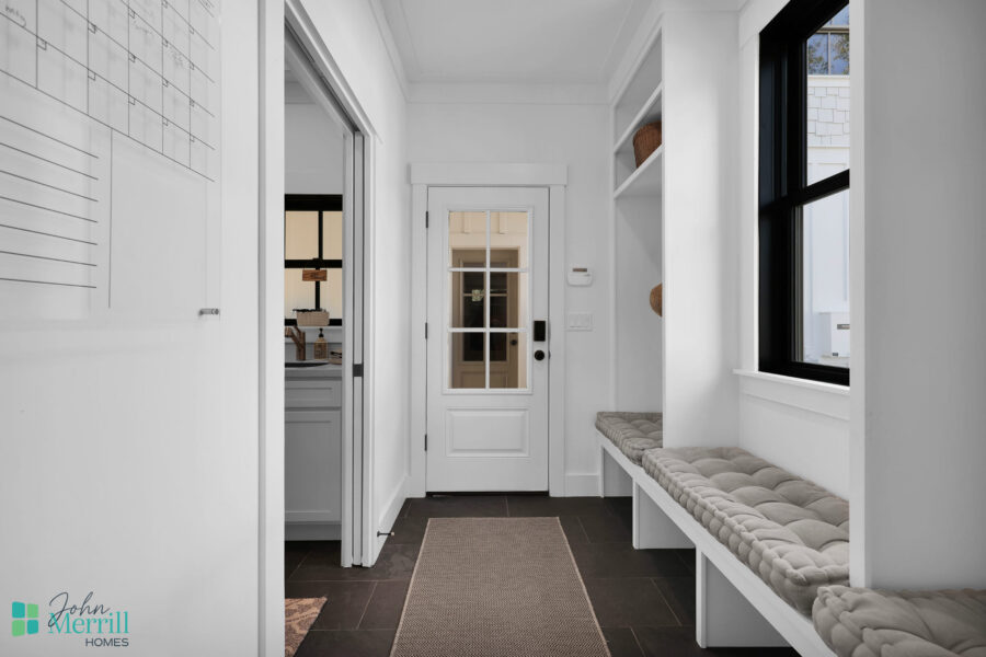Bright and welcoming entryway featuring a built-in bench, large windows, and a white door with glass panels, creating an inviting atmosphere for residents and guests.
