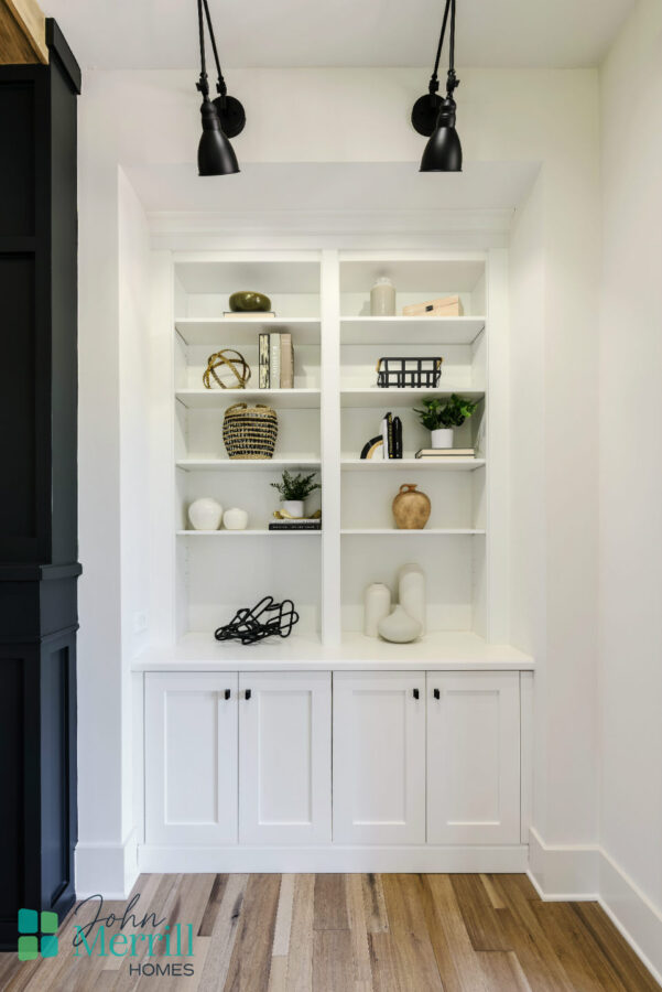 Built-in white bookshelf with decorative objects and books in a well-lit room.