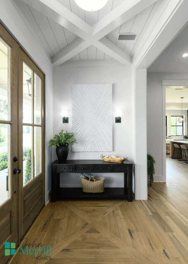 Elegant entryway featuring a wooden door, a black console table, and contemporary wall art in a bright, open home interior.