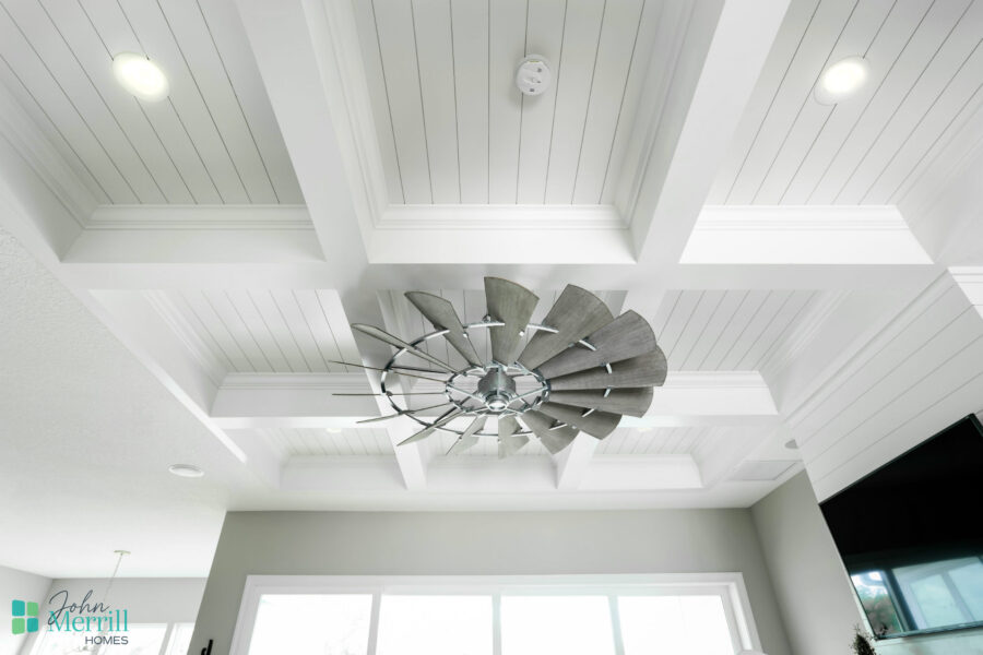 Elegant ceiling fan featuring a contemporary spiral blade design, installed on a white coffered ceiling in a bright, airy living space.