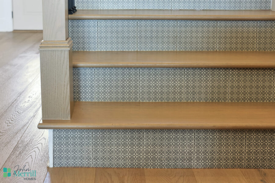A close-up of a staircase featuring wooden treads and patterned tile risers, highlighting stylish interior design elements.