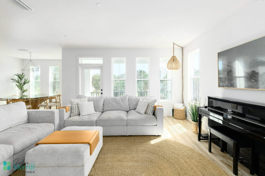 A spacious, contemporary living room featuring large windows that fill the space with natural sunlight, comfortable gray sofas, and stylish decor, creating an inviting atmosphere.