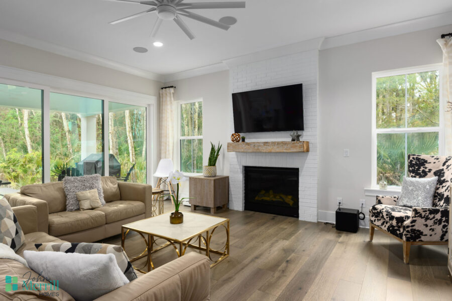 Bright and airy living room featuring a white brick fireplace, wall-mounted TV, and comfortable seating with neutral tones.